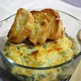 Delicioso plato de espinacas con bechamel gratinado, coronado con tostaditas de pan.