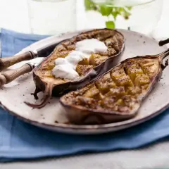 Berenjenas al microondas, cortadas por la mitad y rellenas, con una cucharada de yogur encima.