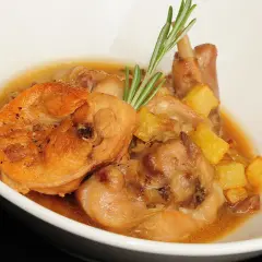 Delicioso conejo en salsa con patatas y romero, servido en un cuenco blanco.