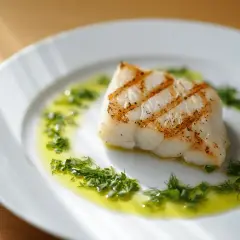 Un delicioso bacalao a la plancha, con marcas doradas, servido en un plato blanco con aceite de oliva y hierbas frescas.