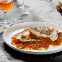 Delicioso plato de urta a la roteña, con pescado blanco y verduras en salsa, acompañado de una copa de vino.