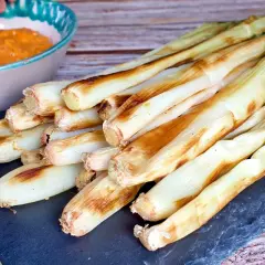 Calçots al horno, tiernos y dorados, listos para mojar en salsa romesco. Un festín de sabor.