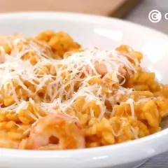 Un cremoso risotto de gambas, cubierto con queso rallado, listo para disfrutar.
