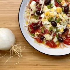 Deliciosa ensalada murciana con tomates, huevos duros, aceitunas negras y cebolla tierna, lista para disfrutar.