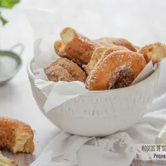 Roscos de Semana Santa espolvoreados con azúcar, servidos en un cuenco blanco.