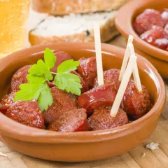 Delicioso chorizo a la sidra en cazuela de barro, adornado con perejil fresco. Acompañado de pan y una cerveza.