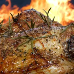 Pierna de cordero al horno, dorada y jugosa, con romero fresco y especias, lista para ser disfrutada.