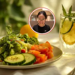 Una mujer sonríe mientras disfruta de una refrescante ensalada de pepino y una bebida con limón y pepino.