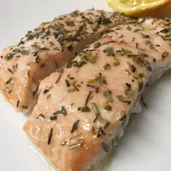 Dos jugosos filetes de salmón al horno, cubiertos con hierbas aromáticas y un toque de limón.