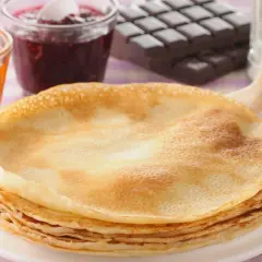 Una pila de crepes doradas, listas para disfrutar con mermelada de frutos rojos, albaricoque y chocolate. ¡Una deliciosa receta crepes!