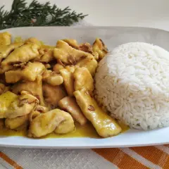 Sabroso pollo al curry cremoso servido con una porción generosa de arroz blanco.