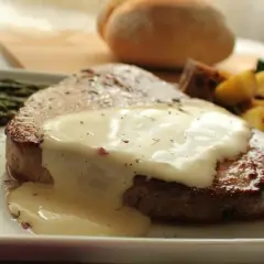 Jugoso redondo de ternera bañado en salsa cremosa, acompañado de espárragos y patatas asadas.