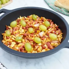 Migas manchegas con uvas verdes y ajos en una sartén. Un plato tradicional listo para disfrutar.