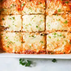Una deliciosa lasaña de berenjena recién horneada, cubierta de queso derretido y perejil picado, lista para servir.