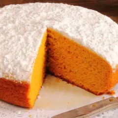 Pastel de zanahoria esponjoso, cubierto de azúcar glas, con una rebanada retirada.