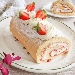 Un delicioso brazo de gitano con crema y fresas, espolvoreado con azúcar glas.