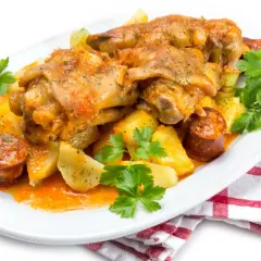 Manitas de cerdo guisadas con patatas y chorizo, decoradas con perejil fresco. Un plato tradicional y sabroso.