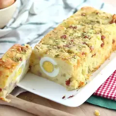 Un delicioso pastel de patata con trozos de bacon y huevos duros en su interior, espolvoreado con hierbas.