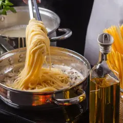 Unos espaguetis se añaden a una sartén con salsa cremosa, listos para convertirse en una deliciosa pasta al ajillo.