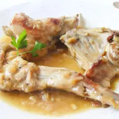 Deliciosas recetas de conejo guisado en salsa, servido en plato blanco con perejil fresco.