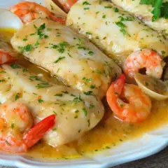 Merluza a la marinera con gambas y almejas, un plato delicioso bañado en salsa.