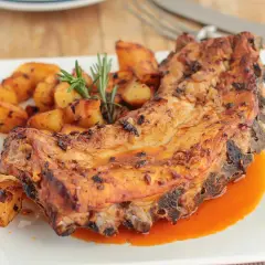 Costillas al horno con patatas doradas y romero fresco. Un plato jugoso y apetitoso.