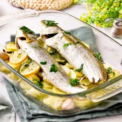 Pescadilla al horno con patatas, limón y ajo, recién salida del horno.