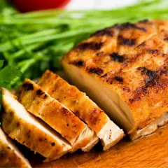 Pechuga de pollo a la parrilla, jugosa y dorada, lista para ser parte de tus recetas con pechuga de pollo. Acompañada de perejil fresco.