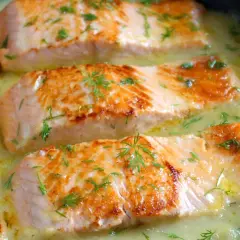Filetes de salmón dorados en una cremosa salsa de eneldo, perfectos para tus recetas con salmón.