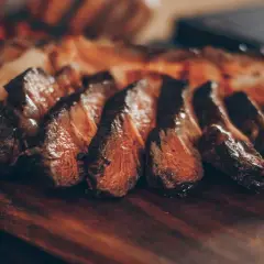 Filete de ternera jugoso y perfectamente cocinado, cortado en rodajas y servido en una tabla de madera.