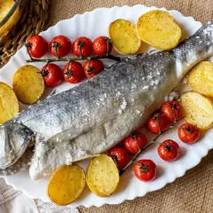 Lubina a la sal entera, horneada con patatas y tomates cherry. Un plato principal delicioso y saludable.