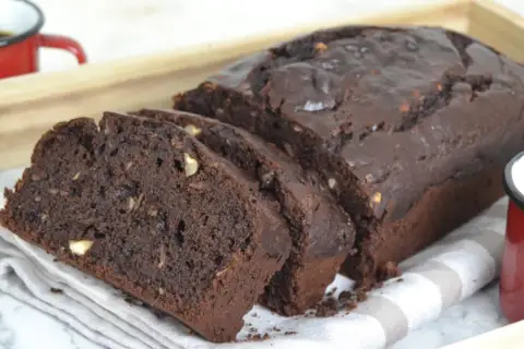 Bizcocho de platano y chocolate, recién horneado y cortado en rebanadas, con trozos de nuez visibles.