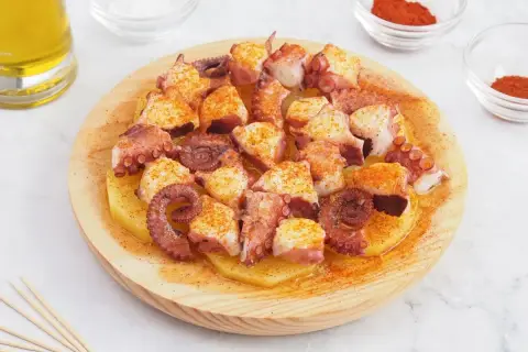 Pulpo a la gallega servido sobre patatas cocidas, espolvoreado con pimentón y aceite de oliva.