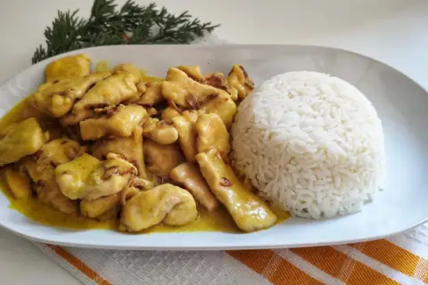 Sabroso pollo al curry cremoso servido con una porción generosa de arroz blanco.