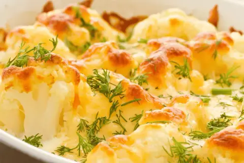 Coliflor al horno gratinada con queso y hierbas frescas. Un plato reconfortante y delicioso.