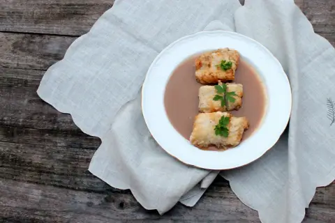 Tres trozos de bacalao rebozado en una salsa cremosa, decorados con perejil. Una de las muchas deliciosas recetas de bacalao.