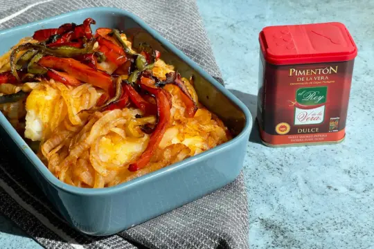 Bacalao a la portuguesa horneado con cebolla y pimientos. El pimentón de la Vera es clave para este plato.
