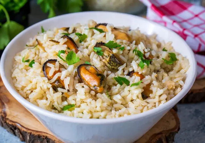 Un tazón de arroz con mejillones y perejil picado. Un plato delicioso y fácil de preparar.