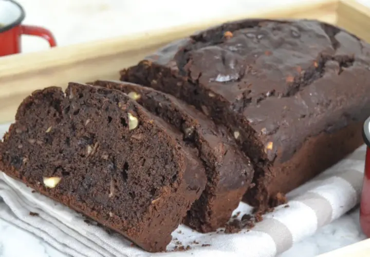 Bizcocho de platano y chocolate, recién horneado y cortado en rebanadas, con trozos de nuez visibles.