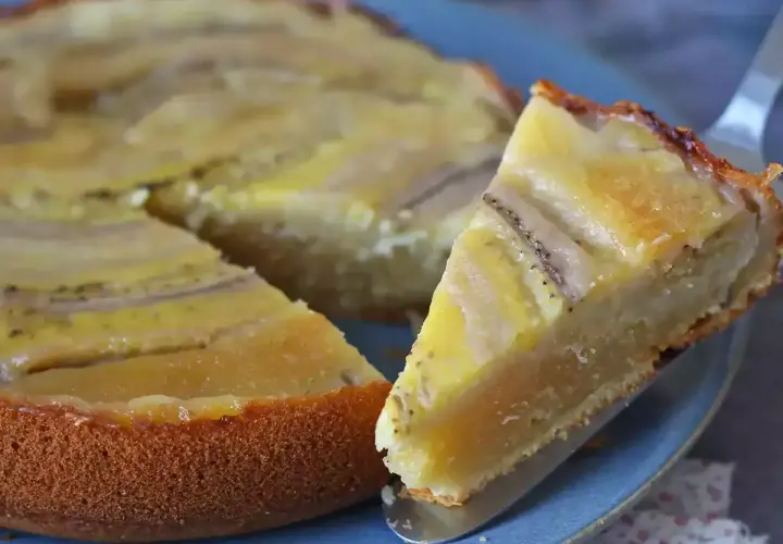 Un delicioso bizcocho de plátano, con una rebanada servida en un plato azul.