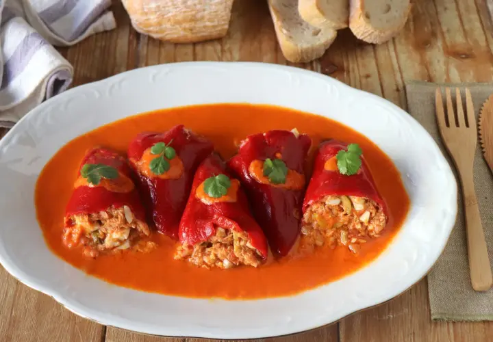 Pimientos del piquillo rellenos de atún y huevo, servidos en una salsa roja cremosa.
