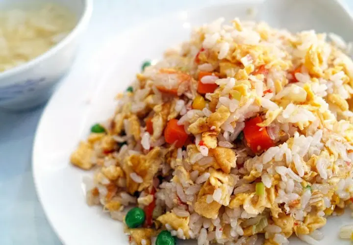 Arroz tres delicias con trozos de huevo, zanahoria y guisantes. Un plato delicioso y colorido.
