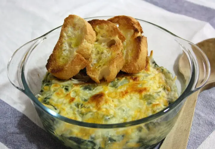Delicioso plato de espinacas con bechamel gratinado, coronado con tostaditas de pan.