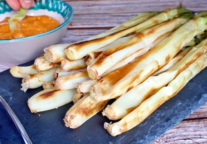 Calçots al horno, tiernos y dorados, listos para mojar en salsa romesco. Un festín de sabor.