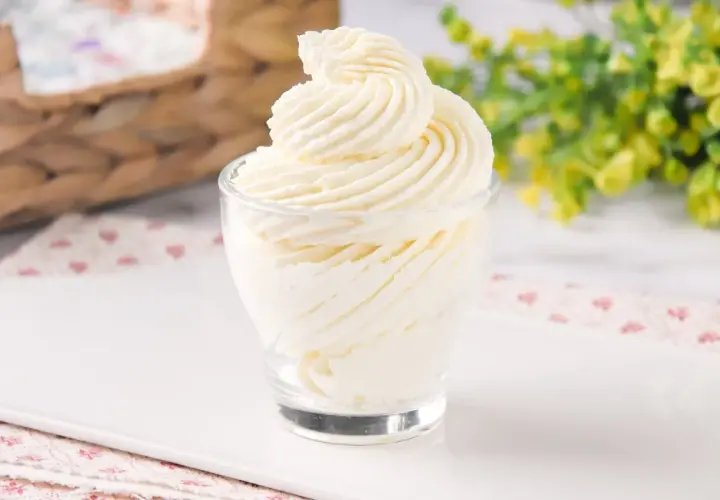 Delicioso frosting de queso cremoso, decorado en espiral, servido en un vaso de vidrio.