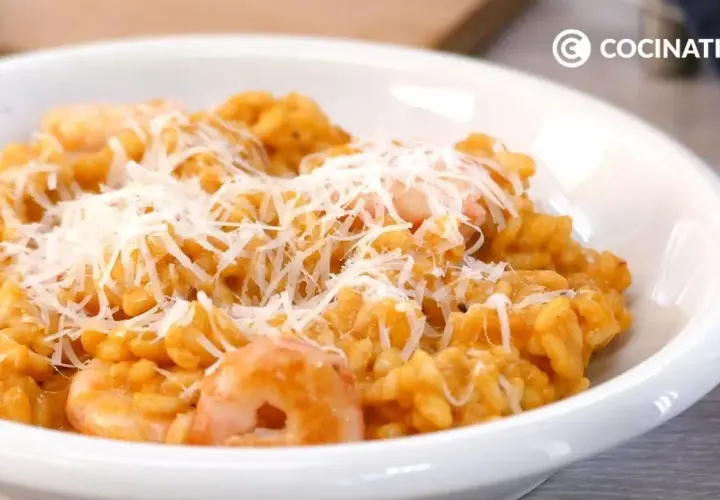 Un cremoso risotto de gambas, cubierto con queso rallado, listo para disfrutar.