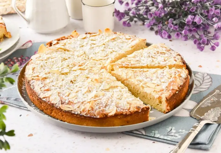 Tarta de almendras, espolvoreada con azúcar glas y almendras laminadas, lista para ser servida.
