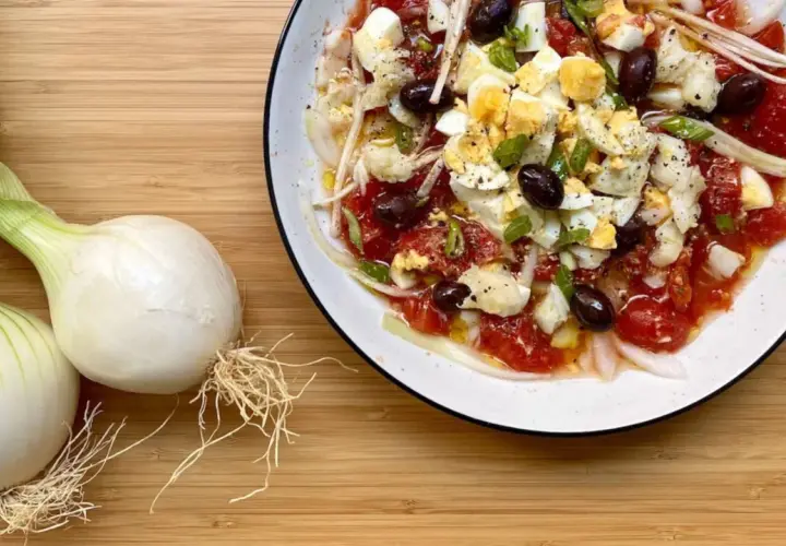 Deliciosa ensalada murciana con tomates, huevos duros, aceitunas negras y cebolla tierna, lista para disfrutar.