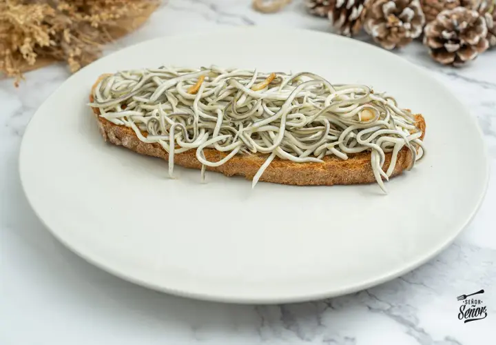 Tosta con gulas al ajillo, un clásico de las recetas con gulas, servida en plato blanco.
