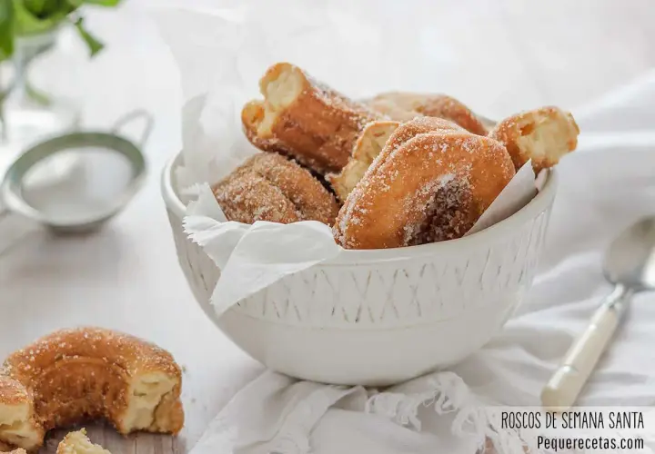 Roscos de Semana Santa espolvoreados con azúcar, servidos en un cuenco blanco.